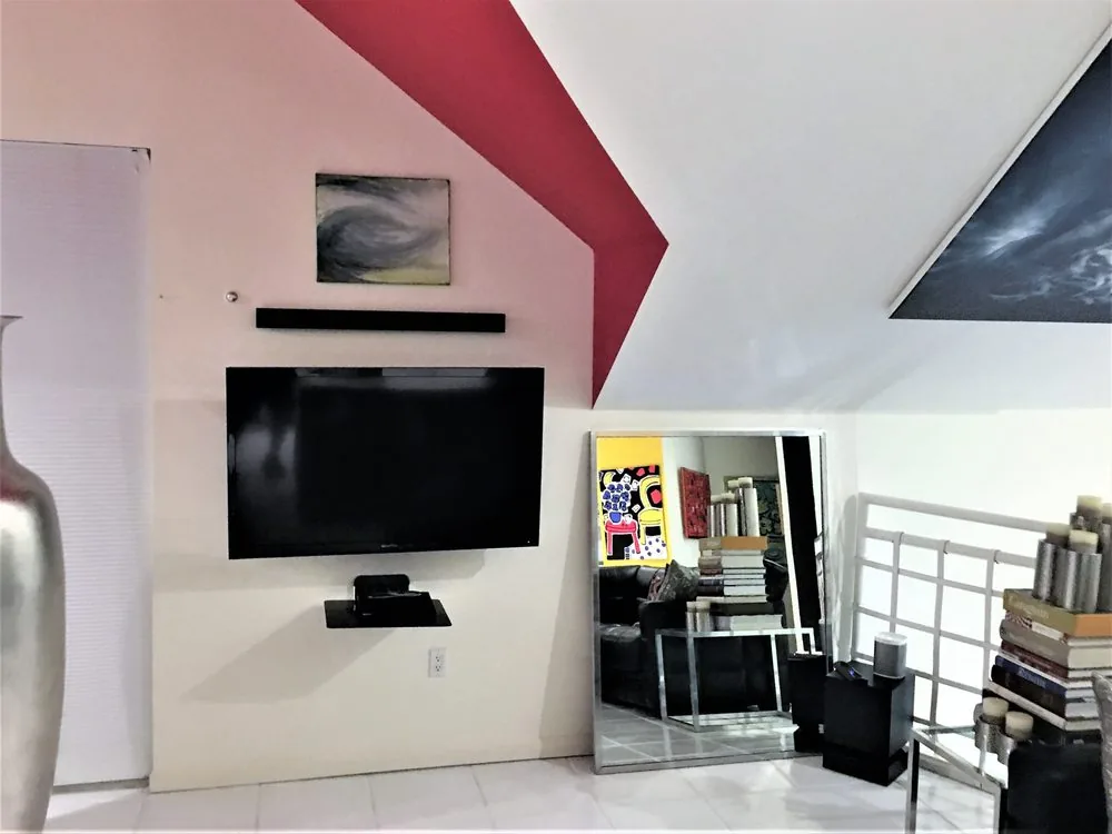 Wall-mounted display and soundbar in a loft, with the streaming box on a small wall shelf