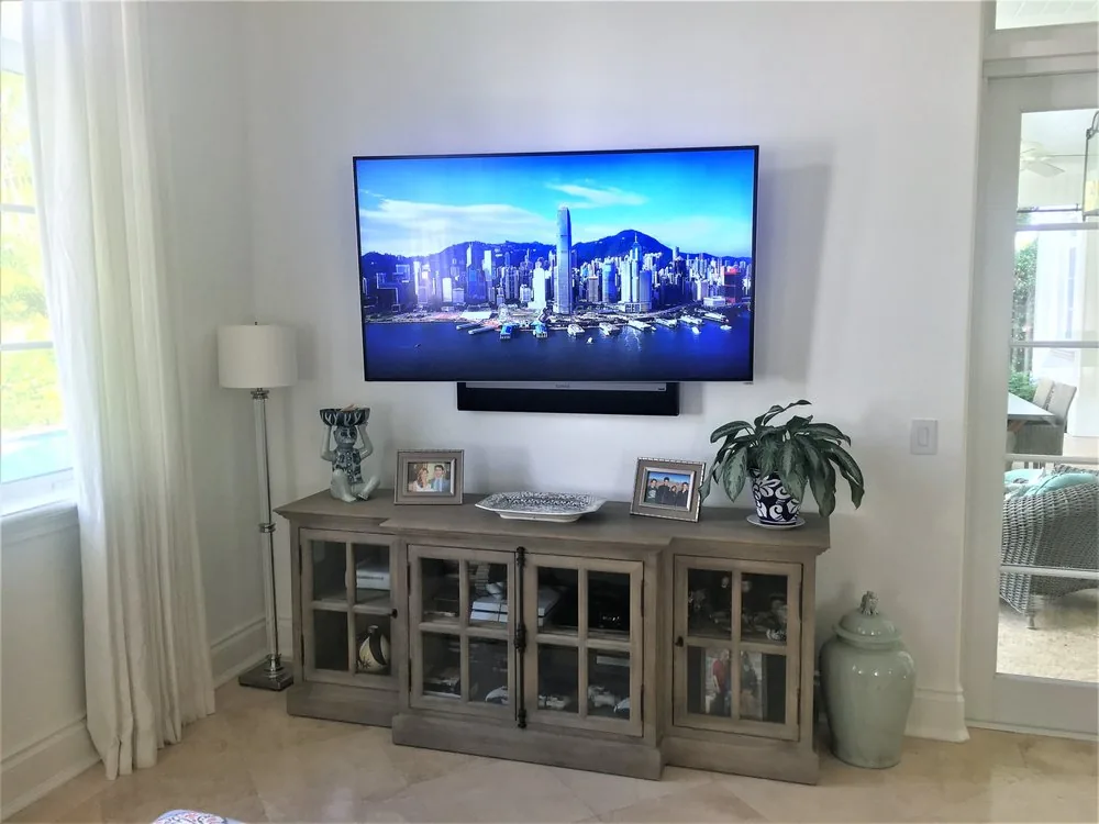 Wall-mounted display and Sonos soundbar over a glass-front console beside the lanai door