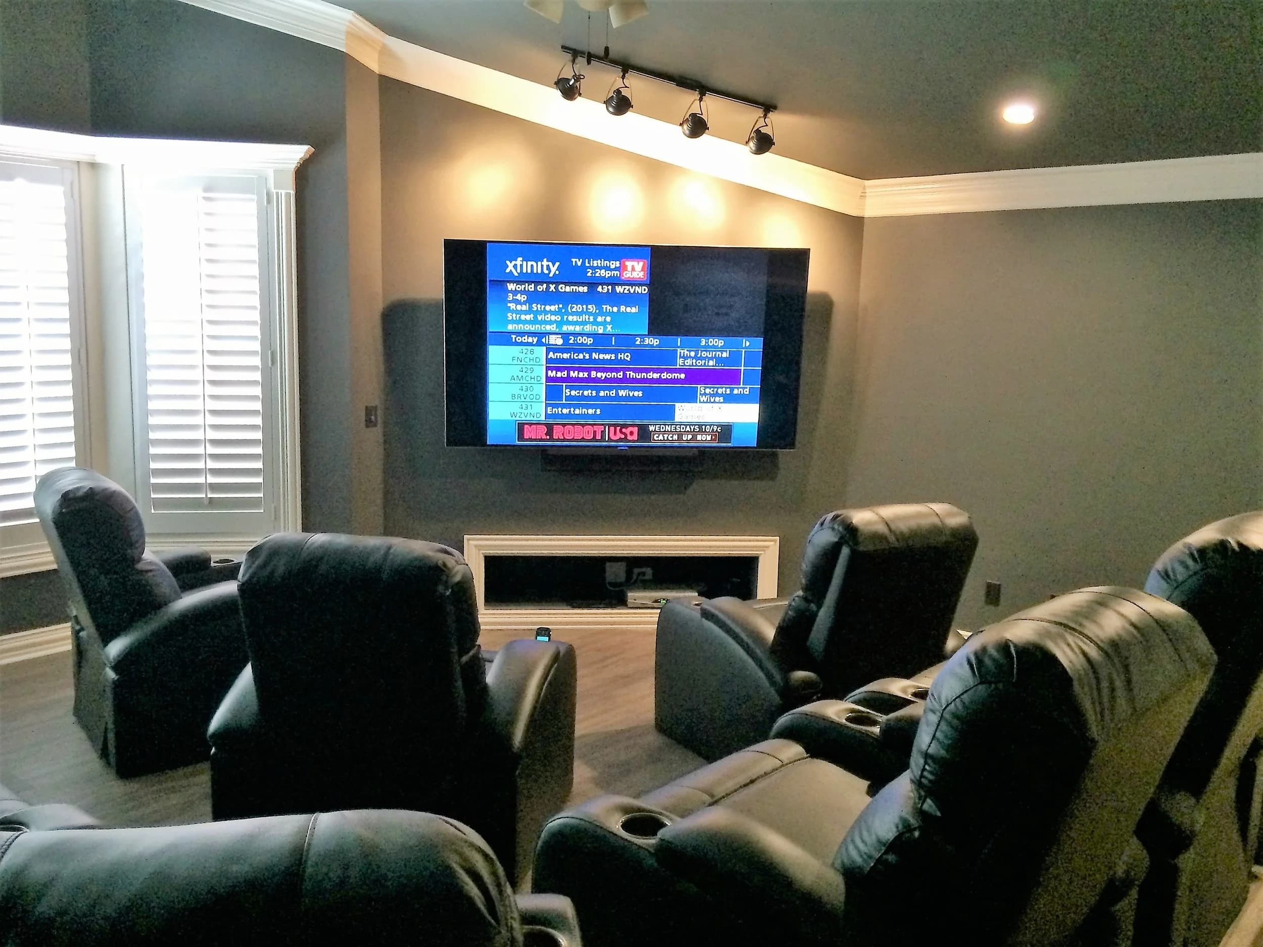 Home theater with tiered recliners facing a wall-mounted display
