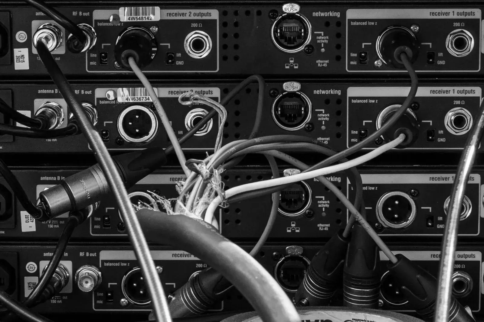 Rear of an audio rack with XLR and coax cables tangled across the equipment